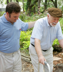 caregiver assisting elderly man in walking